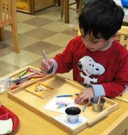 Child painting at an art tray