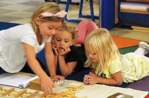 Three children working together with letter materials